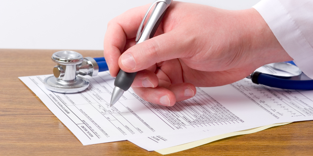 Doctor with pen in hand documenting auto collision injuries