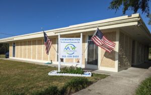Williston Medical Injury Center: Motion Wellness Family Chiropractic Center Office Building Office building with a sign that includes two American flags and that reads Motion Wellness Family Chiropractic Center which is part of the Williston Medical Injury Center Team