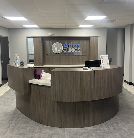 cirular reception desk in center of room with logo sign behind it at Palm Harbor Medical Injury Center: Atlas Clinic