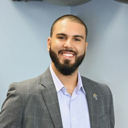 Heashot photo of Dr. Luis Jesus Rodríguez, chiropractor at St Augustine Medical Injury Center: Havlicek Chiropractic, smiling and wearing a black scrub shirt.