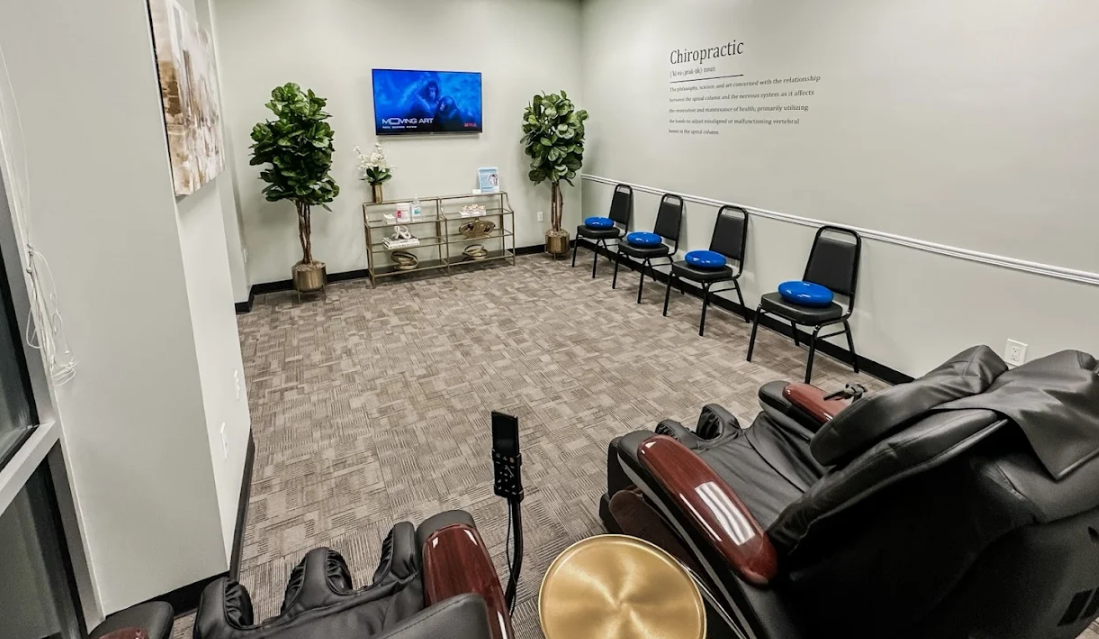 Therapy room with chairs with wobble cushions lined up against one wall, a couple of massage chairs in the foreground, and a tv on the opposing wall at Panama City Beach Medical Injury Center: Balanced Chiropractic