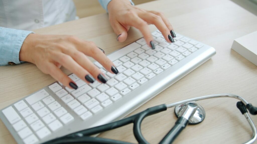 Physician reviewing and documenting medical information on a computer